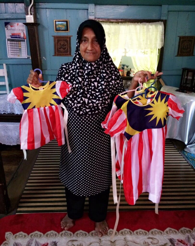Aminah bersama baju Jalur Gemilang untuk cucu-cucunya yang dijahit sendiri.