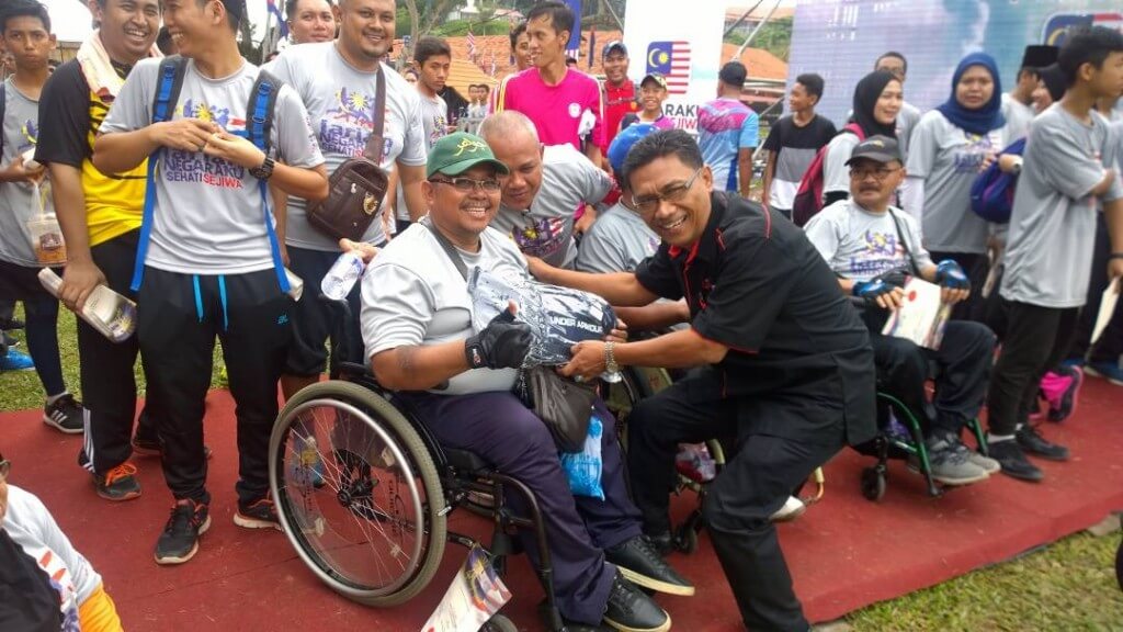Peserta OKU, Izaini Zamzuri menerima hadiah cabutan bertuah daripada Pengarah Jabatan Penerangan Johor, Zainuddin Ismail.