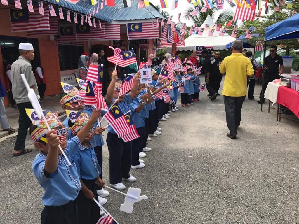 Murid-murid Tabika KEMAS Kampung Sungai Pial mengibarkan bendera bagi menyambut kedatangan konvoi KMN 2017.