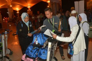 Zaiton (kiri) membantu jemaah semasa pendaftaran masuk di Lapangan Terbang Antarabangsa Kuching.