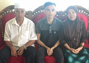 Asai (tengah) bersama ibu bapanya semasa ditemui di kediaman mereka 