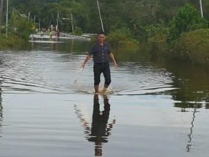 JKKK Kampung Sabandil, Sylvester Lianus (Tengah) mengharungi jalan dinaiki air untuk ke seberang. 