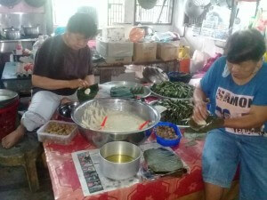 Kim Chu dengan salah seorang pekerjanya sedang menyediakan tepung bungkus dan kuih bakul untuk dijual.