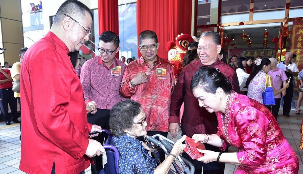  Isteri Timbalan Presiden PBS, Datin Vicky Lai Nyat Yin (kanan) menyampaikan paket Ang Pau kepada salah seorang pengunjung warga emas sambil disaksikan Dr. Yee Moh Chai (kiri), Maximus (tengah) dan Pairin (dua kanan).