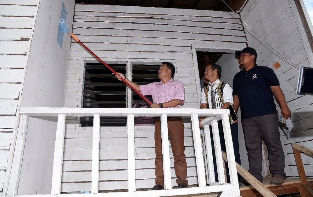 Raime mengecat rumah Bontongan (tengah) sebagai simbolik merasmikan pembaikan rumah berkenaan