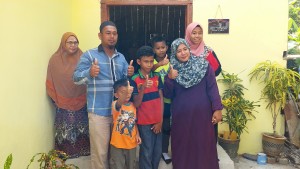 Zafarah (kanan, depan) bersama-sama ahli keluarganya menunjukkan isyarat gembira menerima pembaikkan rumah sempena program CTU-NBOS, di sini.