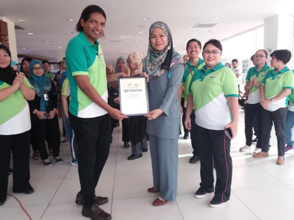 Dr. Yogendran (Kiri) menyampaikan hadiah dan sijil Pertandingan Stor Terbaik kepada wakil daripada unit pengurusan hospital. 