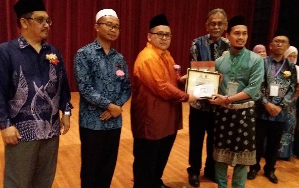 Junaidi ( tiga kiri hadapan) menyampaikan hadiah dan sijil kepada Johan Qari Pertandingan Tilawah Al-Quran kepada Muhamad Taufiq mewakili Pejabat Kesihatan Kawasan Kota Kinabalu.