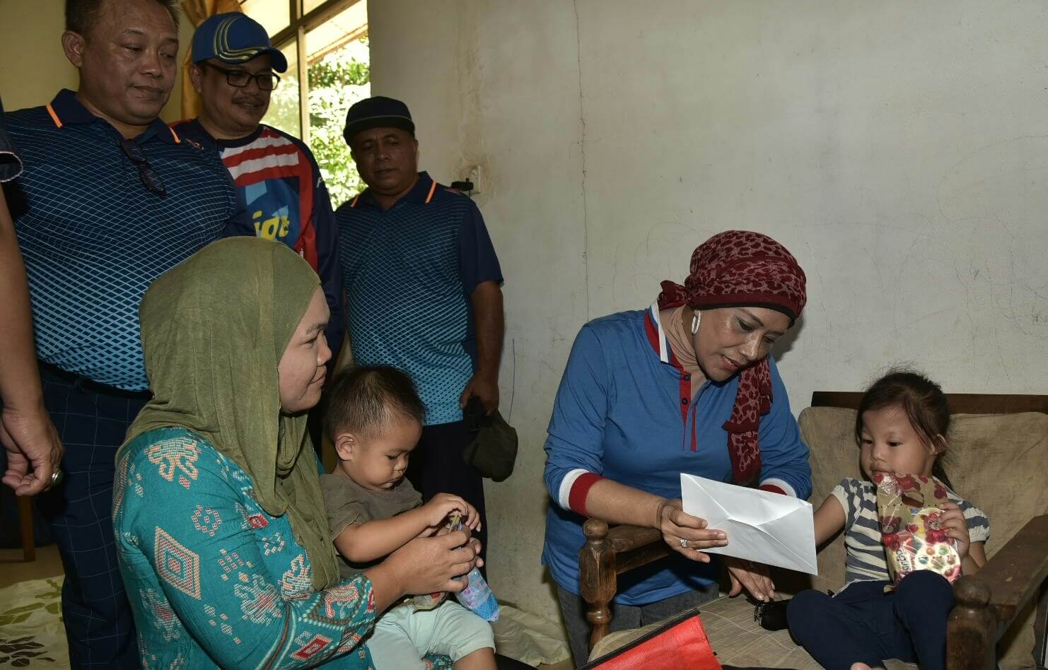 Sharifah Zaharah menyampaikan bantuan kawangan kepada kanak-kanak OKU Nur Awfiyah Zahra Mardi (5 tahun) (kanan) yang mengalami masalah pendengaran dan saluran nafas sempit di Kampung Tengkurus.