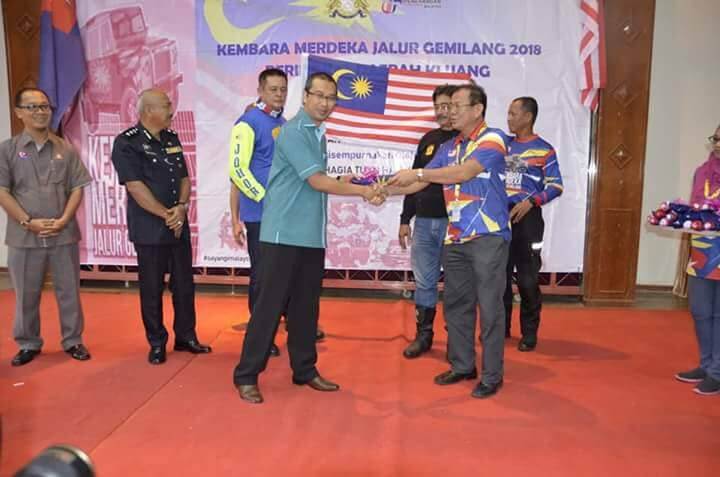 Ketua Konvoi KMJG 2018, Lim Ann Teck menyerahkan Jalur Gemilang kepada Pegawai Daerah Kluang, Ismail Abu 