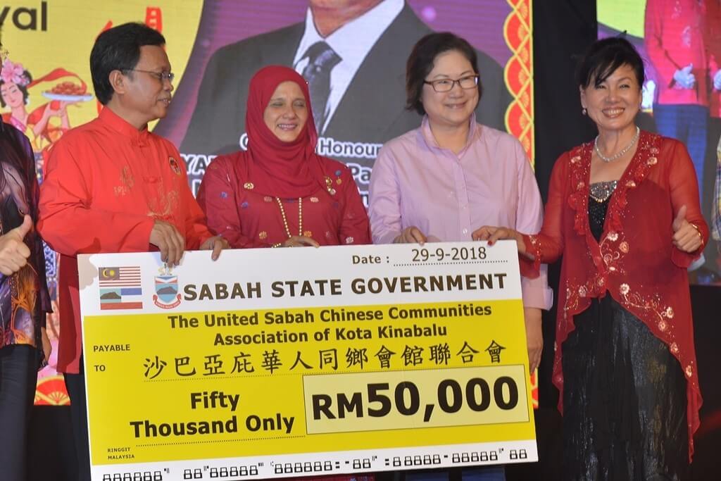 Mohd Shafie (kiri) menyampaikan replika cek RM50 ribu sebagai sumbangan kerajaan negeri kepada Presiden Persatuan Masyarakat Cina Bersekutu Sabah (USCCA) Kota Kinabalu, Datuk Susan