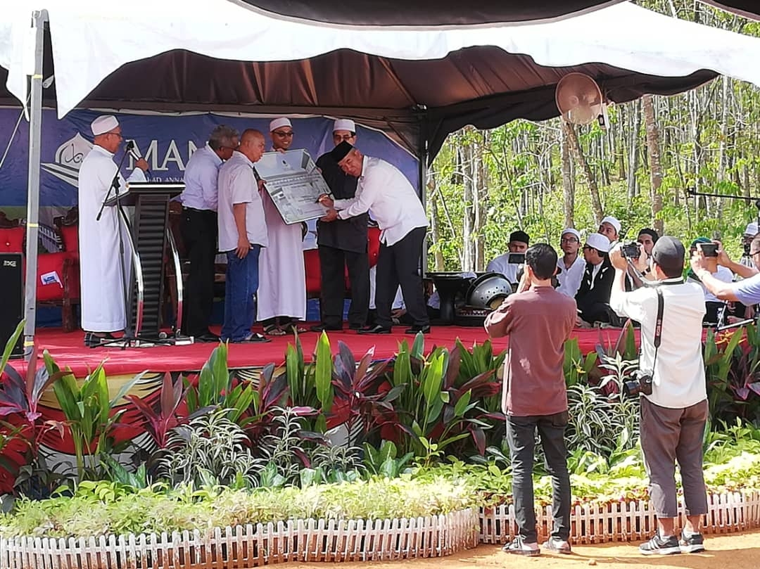 Mohamad Che Nai (berkopiah hitam) menandatangani replika cek RM3000 sumbangan dari Pejabat Daerah dan Tanah Kulim.