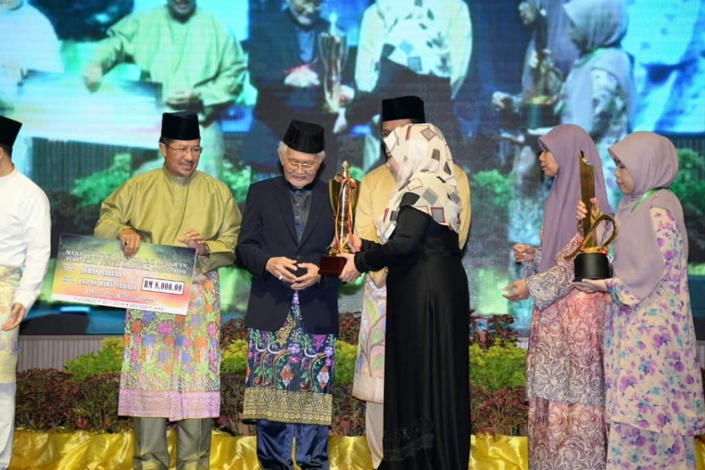 Tun Taib menyampaikan hadiah kepada Johan Qariah Nur Syakura  Mohamad Musa mewakili Bahagian Kuching