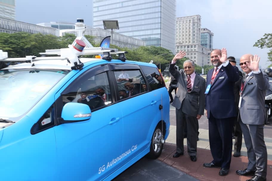 Perdana Menteri dan Menteri KKMM (tengah) menunjuk isyarat 5G selepas menyaksikan 'Autonomus car' di pameran 5G Malaysia