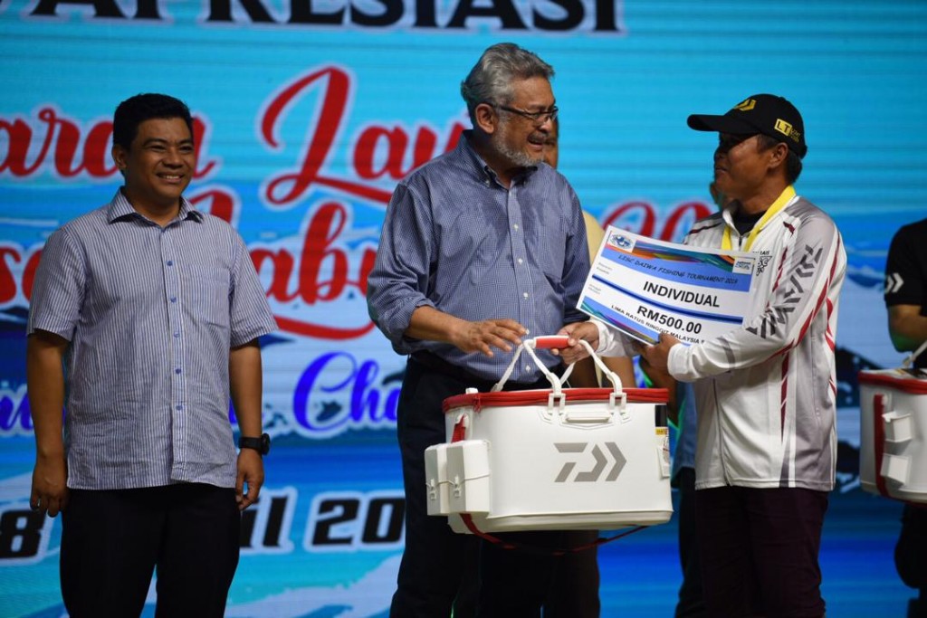 Salah seorang pemenang pertandingan memancing kategori individu menerima hadiah daripada Khalid (tengah)