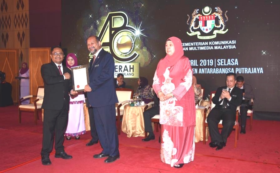 Azman Jumat ketika menerima sijil daripada Gobind(tengah) sambil diperhatikan oleh Timbalan Ketua Pengarah Komunikasi Strategik JaPen, Roselindawati Abdul Rahman