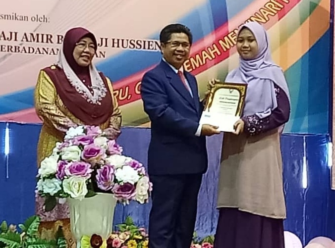 Raisin (tengah) menyampaikan Anugerah Anak Guru Cemerlang kepada anaknya Izyan Zahirah Raisin,17.