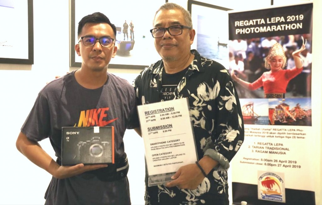 Amri(kanan) menyampaikan hadiah tempat pertama kategori kamera DSLR kepada Mohd Zaini(kiri).