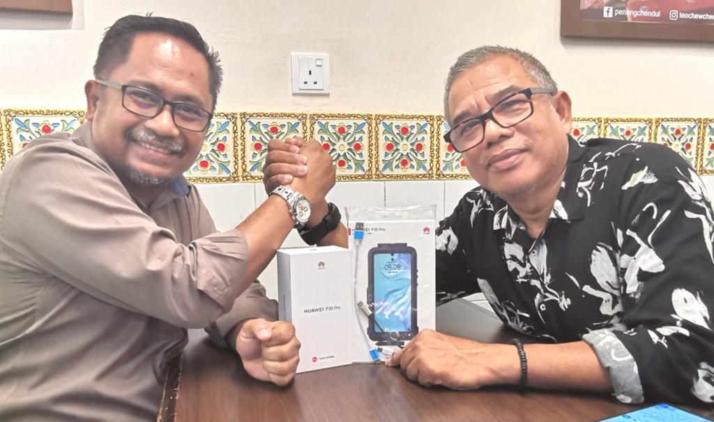 Azman (kiri) menerima Huawei P30 kerana memenangi tempat pertama kategori telefon pintar daripada Amri(kanan).