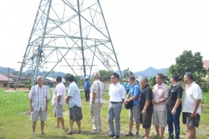 Beberapa penduduk kampung menyaksikan pekerja kontraktor menurunkan struktur menara penghantaran projek CAR.