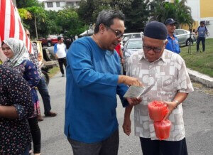 Erwin (berbaju biru) memberi penjelasan berkaitan isu semasa dalam risalah yang diedarkan kepada penduduk.