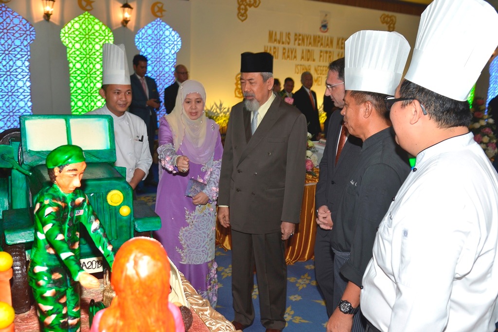 Toh Puan Norlidah mengatakan sesuatu mengenai kek kepada Tun Juhar (tengah) sambil diperhatikan warga Hyatt Regency Kota Kinabalu