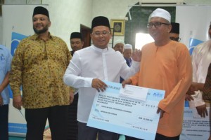Amirudin (tengah) menyampaikan sumbangan kepada wakil masjid dan surau.