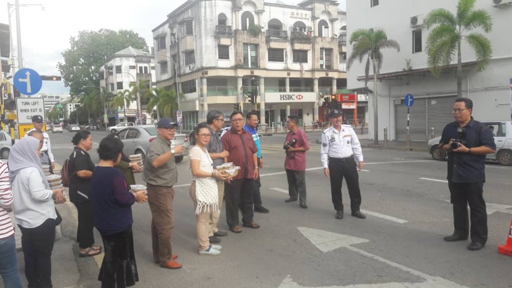 B Chiew Chiu Sing bersama Abg Sardon Abg Hj Hashim mengagih bubur pedas kepada pengguna jalan raya