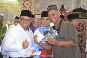 Salah seorang bakal haji menunjukkan insentif Haji Muassasah Selangor yang disampaikan Menteri Besar, Amirudin Shari (kiri) di Batu Caves hari ini.