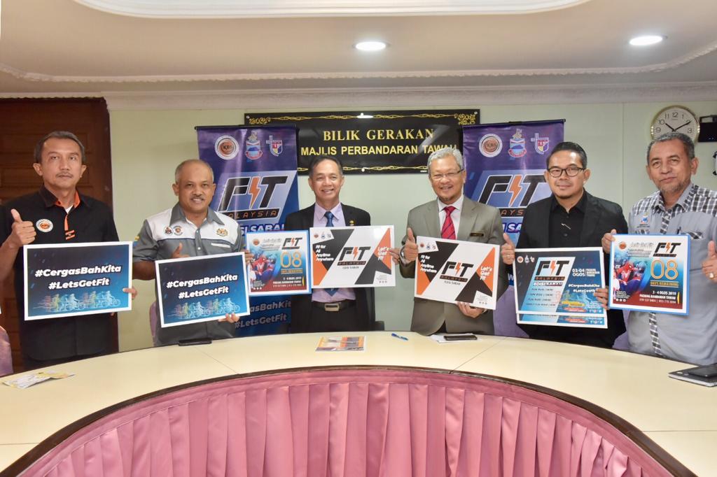 Tetamu kehormat pada sidang media tersebut menunjukan poster program FitMalaysia. 
