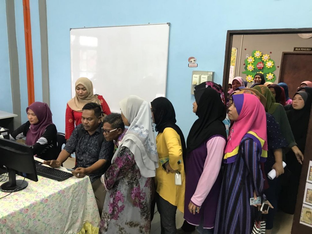 Pegawai Penerangan Tanah Merah, Wan Arif Fadhilah sedang membantu peserta menyemak senarai e-kasih secara atas talian