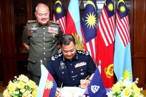 Datuk Seri Abdul Hamid (duduk) menandatangani buku pelawat semasa lawatan tersebut.