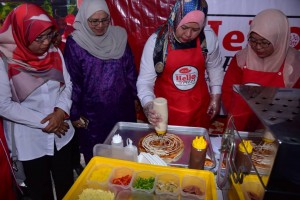 Datuk Seri Rina Mohd Harun membuat demonstrasi penyediaan pizza di Karnival Makanan Desa. 