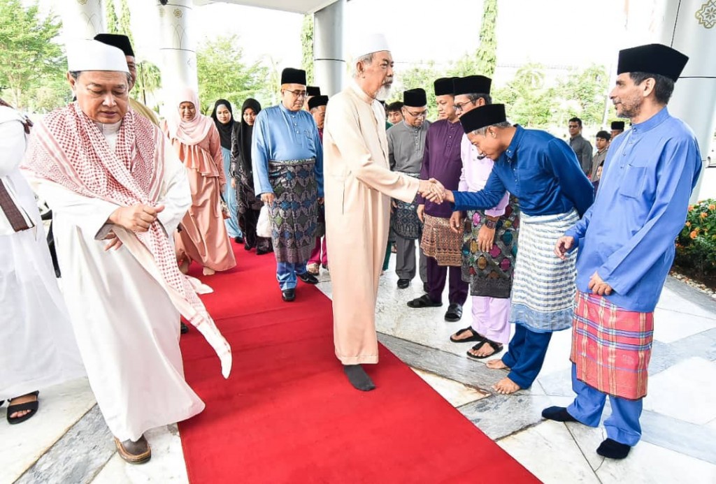 Timbalan Setiausaha Persekutuan Sabah, Yahya Sulaiman (dua dari kanan) menyambut ketibaan Tun Juhar dan Toh Puan Norlidah di perkarangan Masjid Negeri Sabah sambil diiringi Aidi (kiri). 