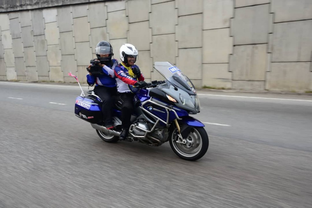 Aksi pengamal media daripada Perbadanan Kemajuan Filem Nasional (Finas) yang mengambil peluang membonceng motosikal berkuasa tinggi sambil membuat rakaman.