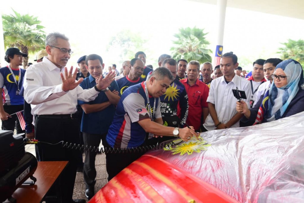 Ketua konvoi KMJG19 Sharom Ravin Daram Abdullah dari Jabatan Penerangan mencuba mengecat kenderaan sebagai simbolik sambutan.