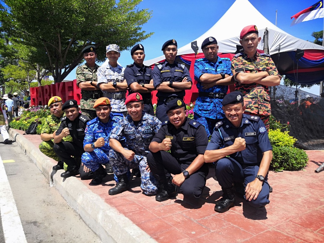 Mohd Dhany (duduk, tengah) bergambar bersama rakan-rakan iaitu anggota-anggota agensi berpakaian seragam rasmi yang turut membaca ikrar dan Rukun Negara. 