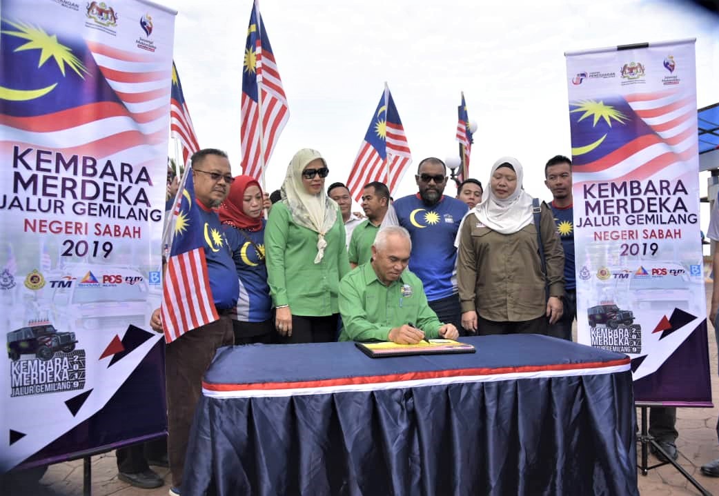 Dr Yusof menurunkan tandatangan pada buku lawatan Konvoi Kembara Merdeka Jalur Gemilang Jabatan Penerangan Negeri Sabah di Dataran Esplanade Sipitang. (foto: Azman Jumat)