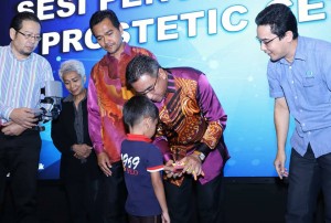 Adly memasang tangan prostetic ciptaan Sujana Rejab kepada adik Amir Firas Herunhizam.