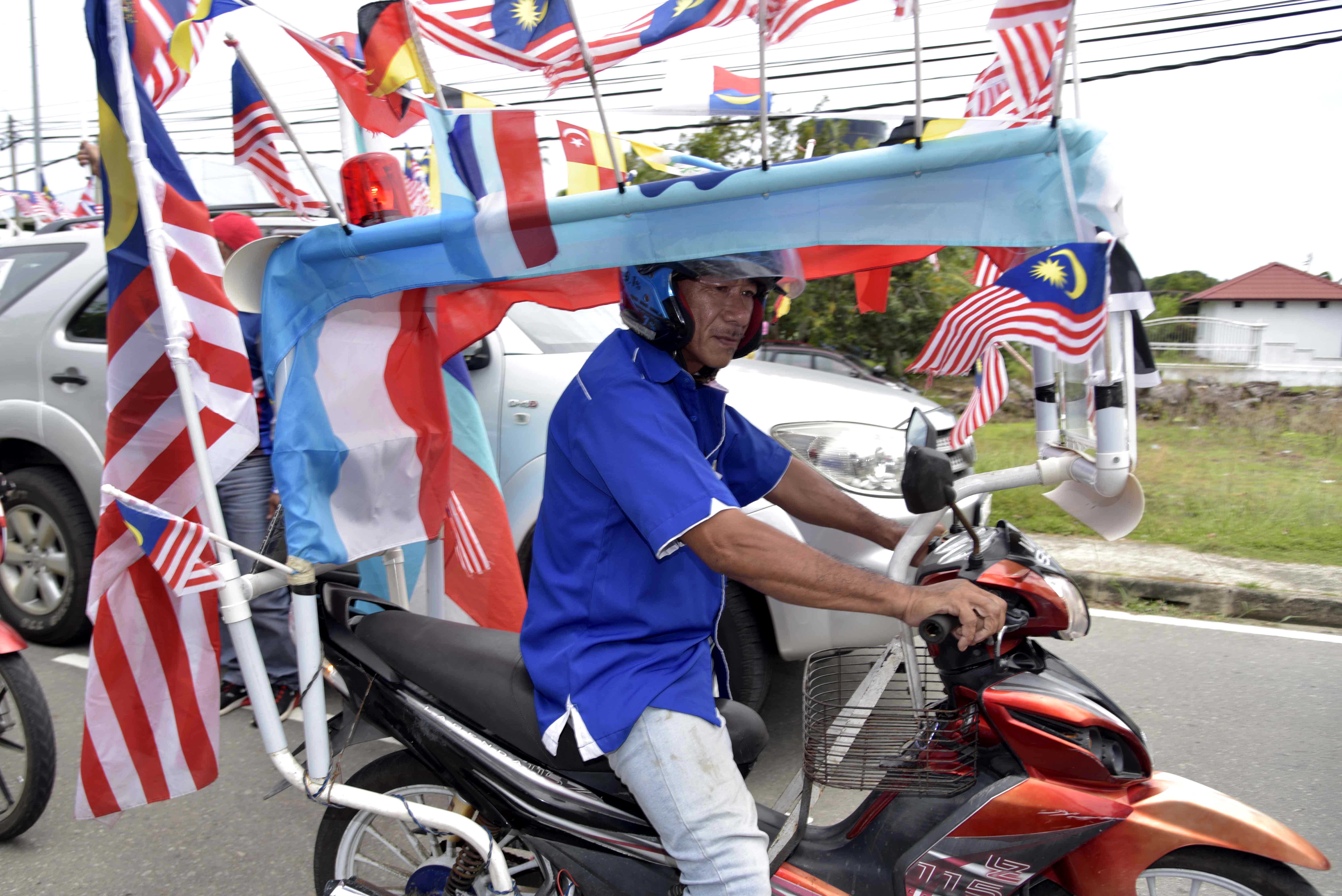 Kelihatan salah seorang penduduk yang menghias motorsikal dengan bendera. 