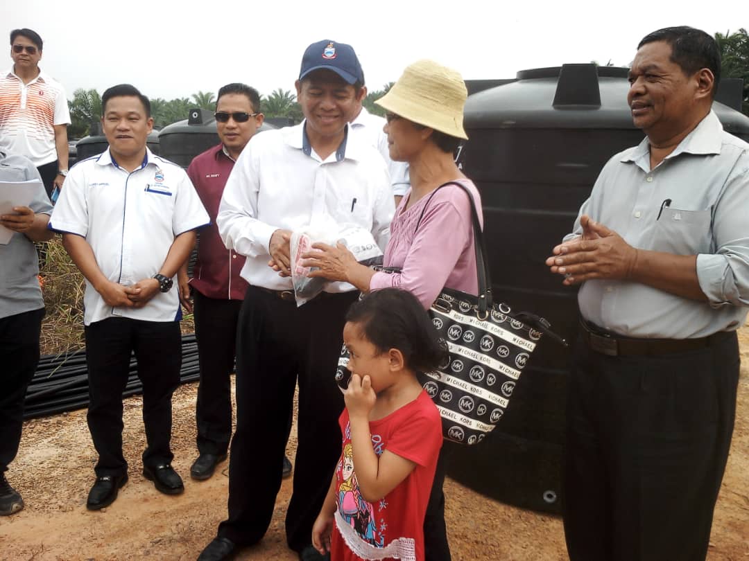 Dr Daud (tengah) menyerahkan peralatan tangki air kepada wakil penduduk Kg Viging (kanan)