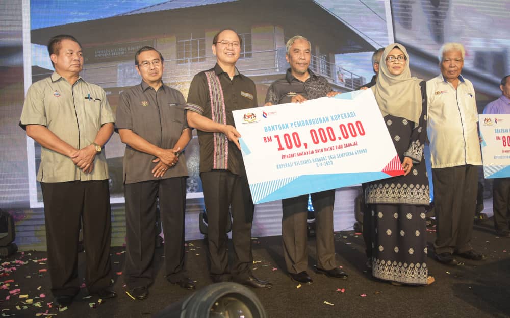 Madius (tiga dari kiri) menyampaikan replika cek bantuan pembangunan RM100,000 kepada Koperasi Keluarga Bagudat Said Semporna Berhad.