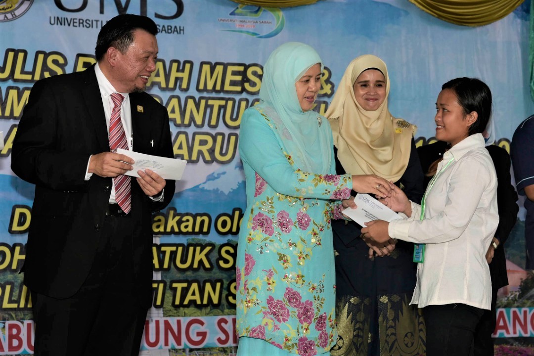 Toh Puan (tengah) menyampaikan bantuan kebajikan pelajar baharu B40 Tahun 1 sambil disaksikan Taufiq (kiri) dan Nur Laila (kanan). 