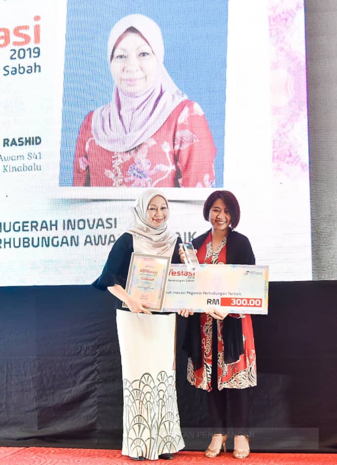 Siti Mariam (kiri) menerima Anugerah Pegawai Perhubungan Awam Terbaik yang disampaikan Ketua Penolong Pengarah, Bahagian Media dan Komunikasi Korporat, Imelda Godon (kanan).