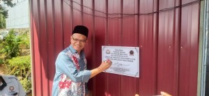Dr Shahrudin menandatangani plak sebagai simbol perasmian pejabat MPKK Kampung Felcra Pinggir Sri Wangi.