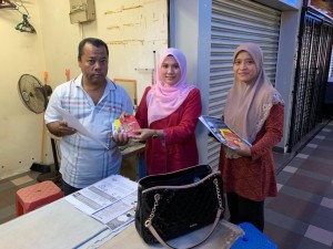 Peniaga, Taufik Muda menerima risalah mengenai 2019-nCoV daripada pegawai lapangan daerah Kuala Terengganu, Maherah Marina Mahusin