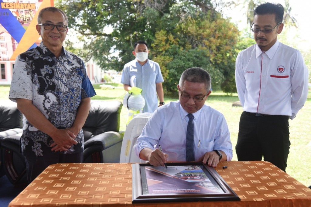 Adham (tengah) menandatangani plak perasmian Projek Kuarters Kakitangan Jabatan Kesihatan Labuan sambil diiringi Ahli Parlimen Labuan, Datuk Rozman Isli (kiri) dan Pengarah Kesihatan Labuan, Dr. Ismuni Bohari (kanan).