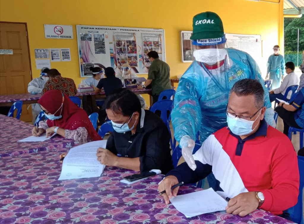 Anggota Jabatan Kesihatan membantu para warga Jabatan Pendidikan semasa proses pendaftaran.