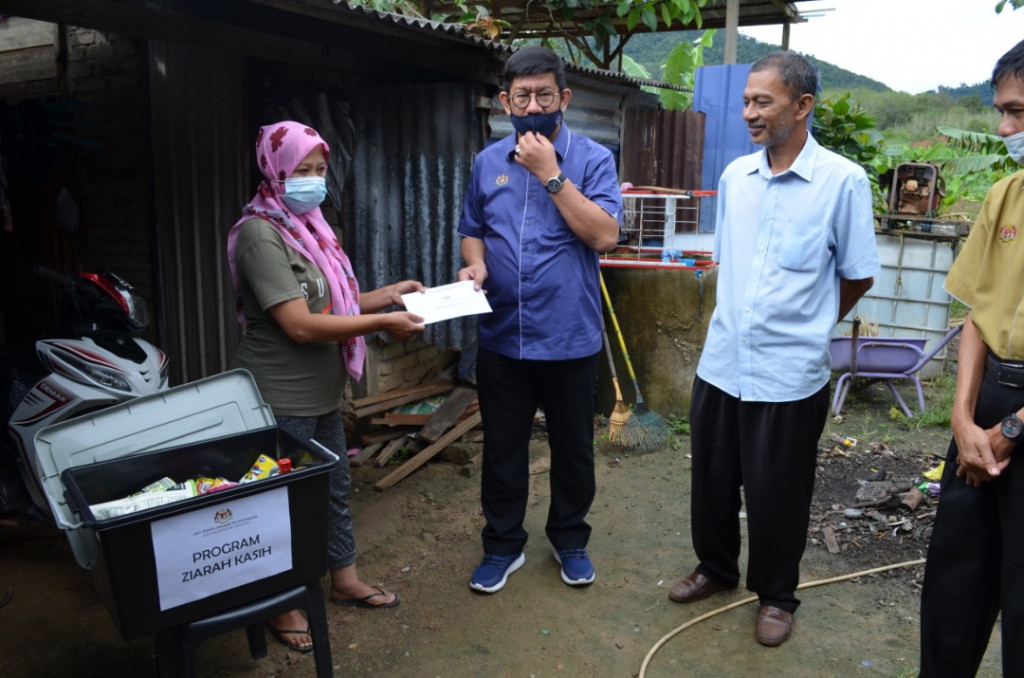 Dr Megat (tengah) menyampaikan bantuan kepada salah seorang penerima dalam Program Ziarah Kasih, di daerah sini.