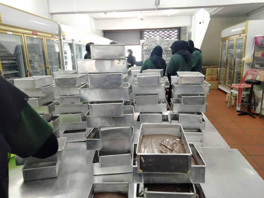 Pekerja-pekerja sedang menyiapkan kek coklat lembap yang telah ditempah pelanggan secara dalam talian.
